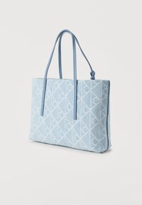 Μπλε τσάντα tote από τζιν με ανοιχτό μπλε δερμάτινα χερούλια. Διαθέτει κεντητό λευκό λογότυπο στο εξωτερικό, ορθογώνιο σχήμα και λεία υφή.