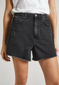 Pantalones cortos de mezclilla negros con dobladillo deshilachado, con una cintura alta, detalles desgastados y bolsillos frontales. Fabricados en tela de algodón.