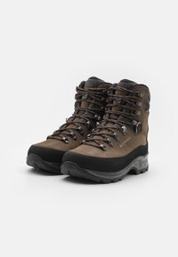 Bruine wandelschoenen met een hoge enkel, rubberen zool, metalen oogjes en een leren bovenkant met textuur, voorzien van een versterkte neus en vetersluiting.