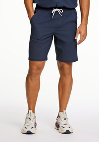 Marina blå shorts i ett texturerat tyg med elastisk midja och dragsko. Har sidofickor och en knälång längd.