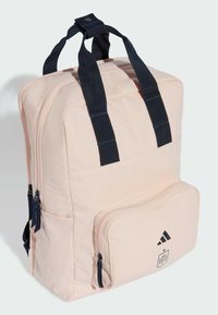 Zaino in tessuto rosa con spallacci blu navy, design rettangolare, struttura imbottita, tasca frontale con zip e stampa del logo Adidas sulla parte anteriore.