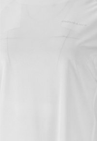 Hvid atletisk t-shirt lavet af letvægts, åndbart stof med en subtil tekstur og et reflekterende "ENDURANCE" logo.