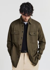 Camicia verde oliva con bottoni realizzata in tessuto morbido, caratterizzata da due tasche a toppa con pattine a bottone, colletto classico e vestibilità comoda.