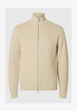 Beige zip-up sweater with a high collar, ribbed texture, and fitted cuffs. The fabric is knit with a subtle pattern, featuring a silver zipper.