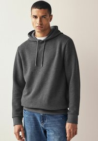 Grå tekstureret hoodie med snøre hætte, forret indeni og ribbede manchetter. Iført med lyseblå denim jeans.