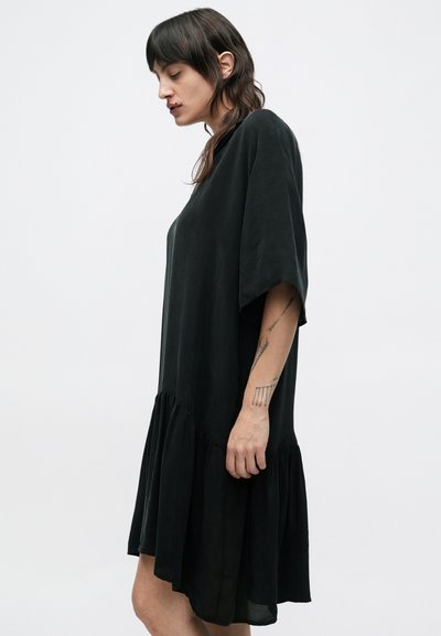 Μαύρο φαρδύ φόρεμα από μαλακό ύφασμα, με κοντά μανίκια και φαρδύ τελείωμα με βολάν.