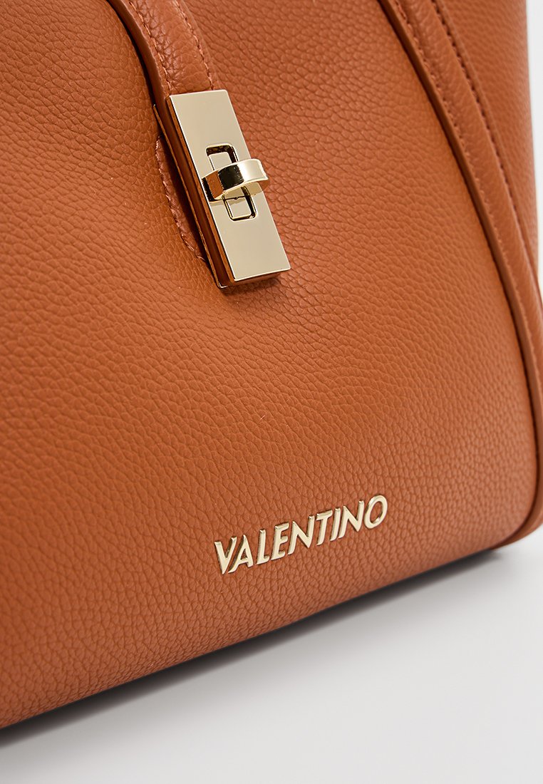 Bruine leren handtas met een gestructureerde afwerking, gouden hardware sluiting en het ingegraveerde "VALENTINO" logo aan de voorkant.