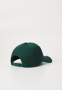 Șapcă de baseball verde închis cu o vizor curbat, dintr-un material moale și cu un sistem de închidere tip snapback ajustabil. Prezintă o textură netedă și nu are modele vizibile.