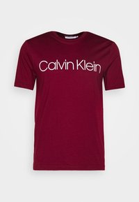 Burgundské tričko z bavlny, krátké rukávy, kulatý výstřih, s velkým bílým nápisem "Calvin Klein" přes hruď. Hladká textury.