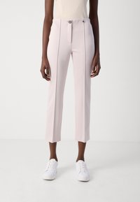 Lichtroze op maat gemaakte broek met een slim fit, voorzien van een sluiting met een knoop aan de voorkant en twee verticale zijnaden, gecombineerd met witte sneakers.