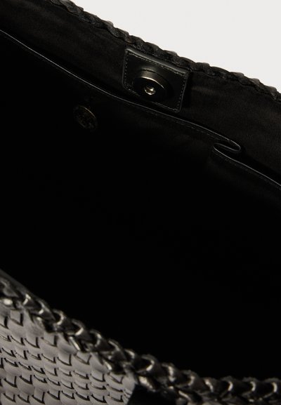 Black woven handbag interior with a smooth texture, featuring a magnetic closure and a small pocket. Accented with braided edges.