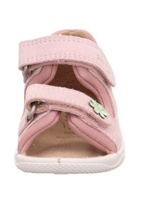 Růžová dětská sandála vyrobená z semišových a textilních materiálů, se dvěma suchými zipy, květinovým akcentem a gumovou podrážkou pro podporu.