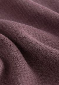 Weicher, strukturierten Stoff in einem reichen Pflaumenton mit feiner Maschenware, die sanfte Falten und subtile Variationen in Dicke und Webart zeigt.