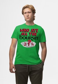 Zelené bavlněné tričko s výrazným černým a červeným textem: "KDO SNĚDL VŠECKY BOURSINY?" s grafikou bílé papírové podložky a otazníku.