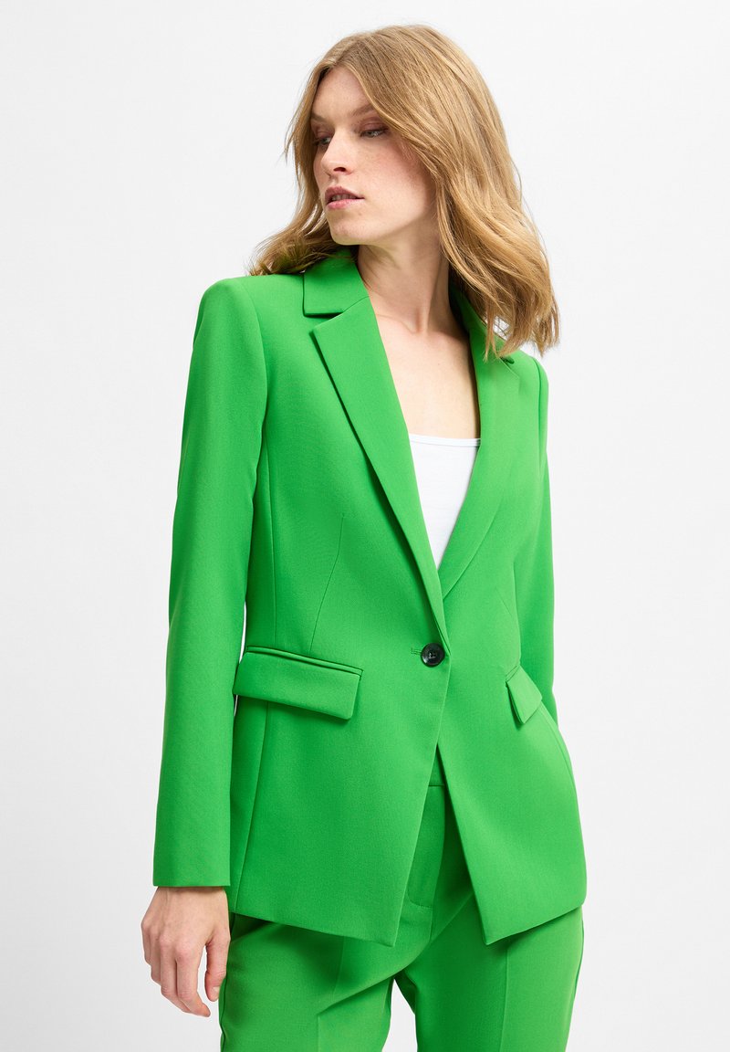 Grüne Blazer aus strukturiertem Stoff, mit Reverskragen, einreihiger Knopfleiste und zwei Vordertaschen. Die taillierte Passform verleiht Struktur.