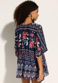 Abito fluido blu navy con vivaci motivi floreali in rosso e rosa, caratterizzato da una vestibilità comoda, maniche a metà e un dettaglio di vita stretta.
