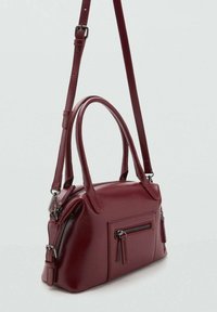 Burgundy nahkahankkainen käsilaukku, jossa on kaksinkertaiset yläkahvat, säädettävä olkahihna ja edessä vetoketjutasku. Silkkinen pinta ja pyöreä muoto.