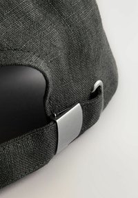 Gray fabric cap featuring a textured finish, adjustable metal clip closure, and a curved brim. The design is simple and functional.