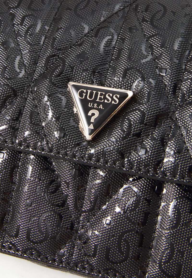 Czarna pikowana torba na ramię z teksturowaną powierzchnią, z trójkątną srebrną plakietką z logo i tłoczonym wzorem stylizowanej litery.