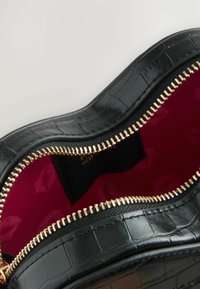 Borsa nera in ecopelle con texture a coccodrillo, zipper dorato e un interno rosa brillante decorato con un motivo di labbra.