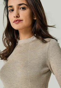 Strickpullover in einem hellbeigen Farbton mit gerippter Textur und Rundhalsausschnitt. Verfügt über Nahtdetails und eine taillierte Silhouette.