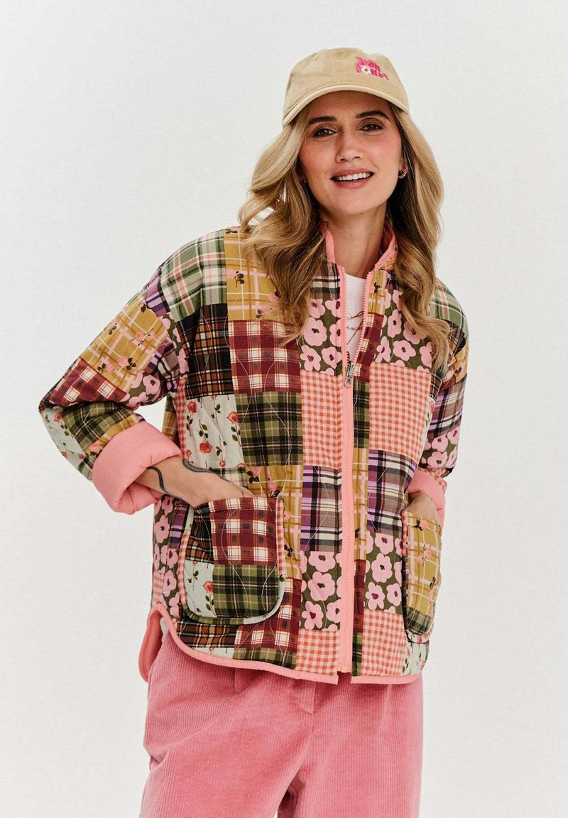 Prošívaná patchworková bunda s různými květinovými a kostkovanými vzory v zelené, růžové, oranžové a žluté barvě; má zipové zapínání a růžové manžety.