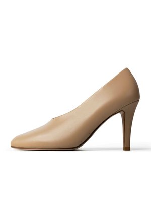 Beige leren pump met hoge hak, spitse neus en slanke naaldhiel, zijaanzicht op een witte achtergrond.