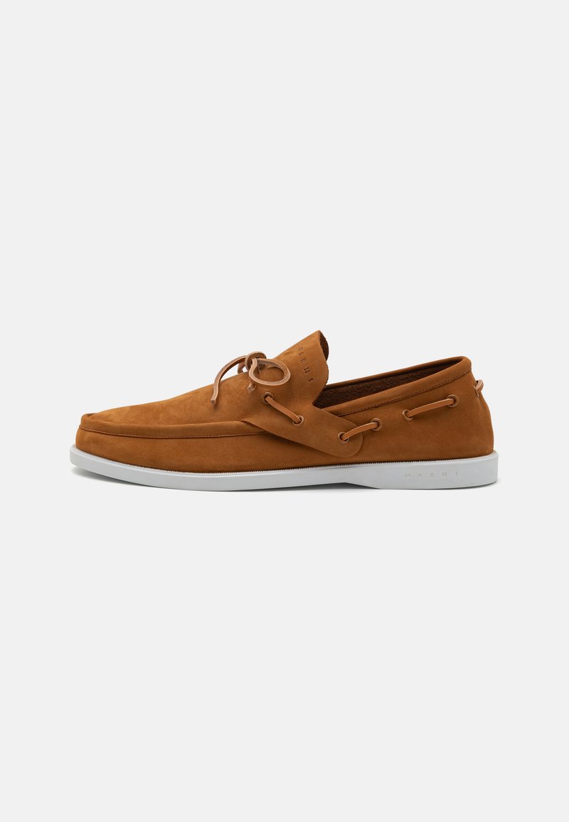 Brown suede boat shoes with a textured finish, featuring white rubber soles and lacing details on the sides for a casual design.