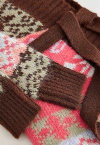 Adīts rakstains džemperis, kas satur brūnos, rozā un krēmkrāsas toņus; iestrādāti riboti piedurkņu gali un dažādi ģeometriski raksti. Mīksta tekstūra.