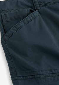Marineblå shorts lavet af blød stof, med en sidelomme og forstærkede sømme. Designet har en glat tekstur og en afslappet pasform.