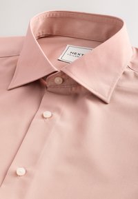 Svijetloružičasta krojena košulja s klasičnim ovratnikom, glatkom teksturom tkanine i bisernim gumbima, s oznakom logotipa blizu vrata.
