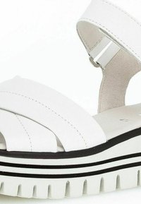 Sandalias de plataforma blancas con correas entrelazadas, un upper texturizado y una gruesa suela blanca acentuada con rayas negras.