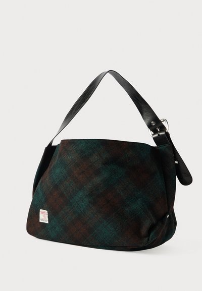 Tumma vihreä ja ruskea ruudullinen kangaskassi leveällä mustalla nahkaremmin ja pienellä kangasbränditarralla edessä.