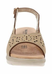 Sandal beige con motivi intagliati, punti dorati, cinturino alla caviglia regolabile, soletta ammortizzata e una suola liscia e testurizzata.