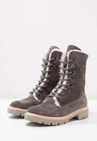 Stivali da trekking in camoscio grigio con rivestimento in shearling, punta rotonda, lacci grigi, occhielli metallici e suola grigia robusta con un accento marrone chiaro.