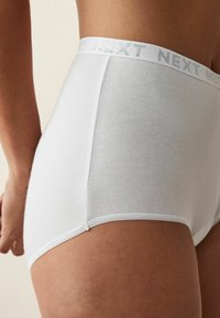 Witte katoenen hoge taille slips met een zachte textuur, voorzien van een zilveren logo tailleband en een gladde stiknaad langs de randen.