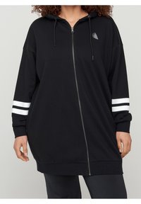 Felpa nera con zip, dal taglio morbido, con cappuccio e dettagli a strisce bianche sulle maniche. Tessuto morbido con un piccolo logo vicino alla zip.