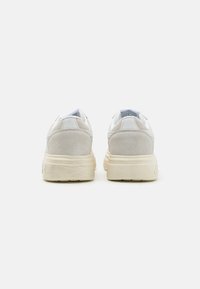 Sneaker in suede grigio e rete bianca con suola texturizzata, caratterizzati da un design a profilo basso e supporto per la caviglia imbottito.