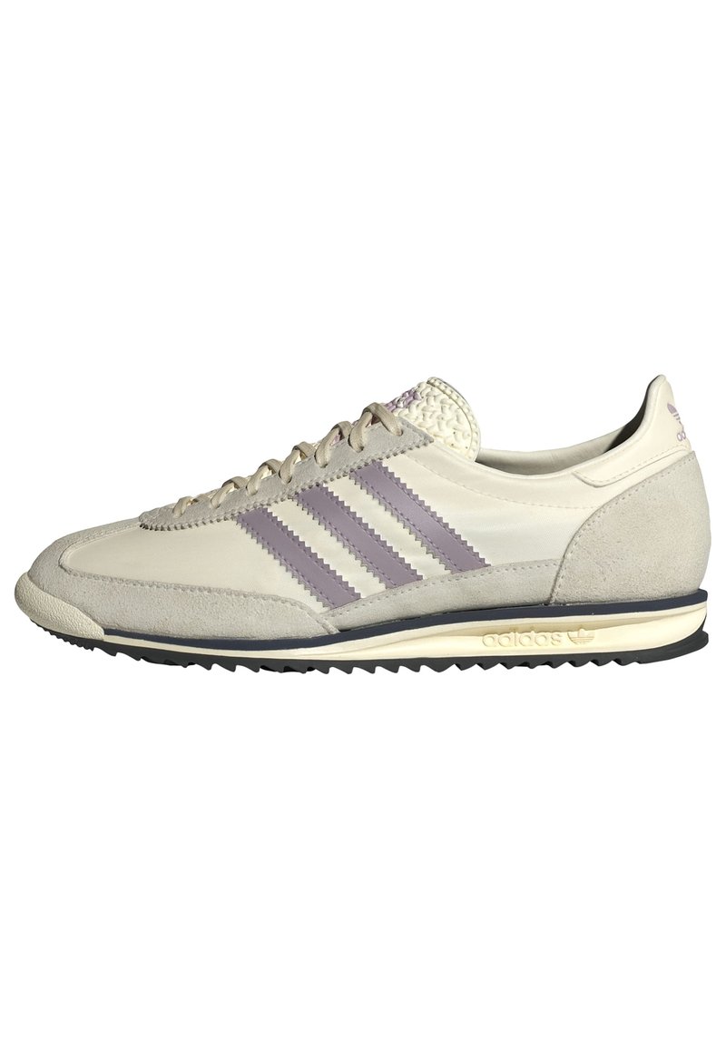 Beige athletic shoe with three purple stripes, suede accents, textured tongue, and black rubber outsole. Classic retro running design.