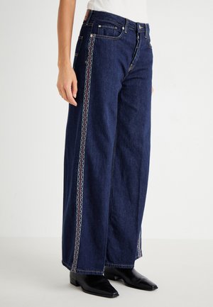 Wide-leg, dark denim jeans featuring red and white embroidered side seams, belt loops, and a classic five-pocket design.