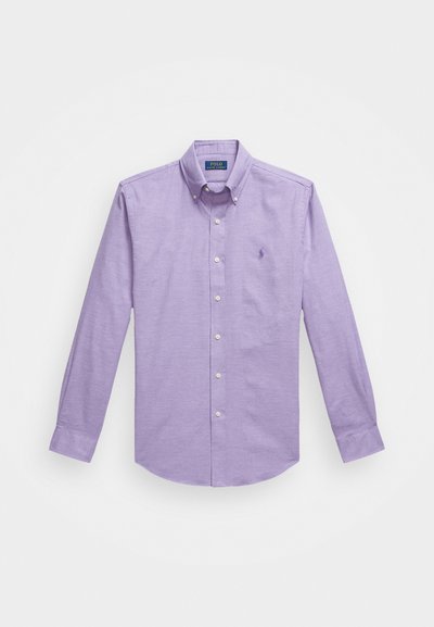 Cămașă cu mâneci lungi, cu nasturi, dintr-un material violet deschis, având un guler clasic și un mic logo brodat pe pieptul stâng.