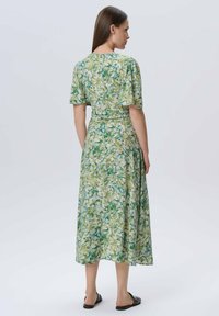 Blumenkleid in Midi-Länge mit einem Muster in Grün, Gelb und Blau, kurzen Ärmeln und tailliertem Schnitt, gefertigt aus leichtem Material.