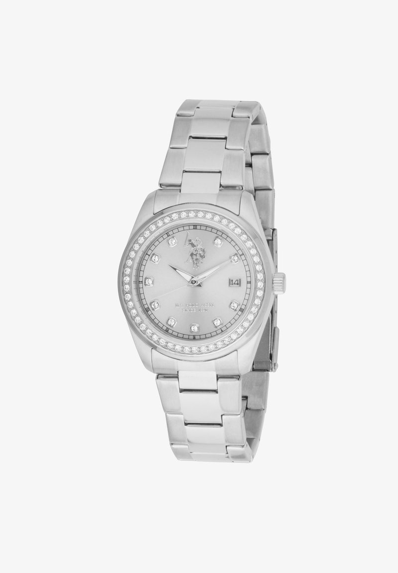 Montre en métal argenté avec un cadran rond, ornée de cristaux transparents, dotée d'un affichage de date et d'un bracelet à maillons.