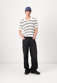 Kortermet polo skjorte med hvite og marineblå striper, sammen med mørke denim jeans og svarte joggesko. Har også en blå caps.