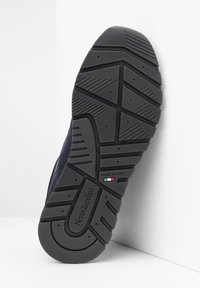 Suola in gomma nera con un motivo di battistrada testurizzato e il marchio "NeroGiardini" in rilievo. Presenta un dettaglio con la bandiera italiana e un design robusto.