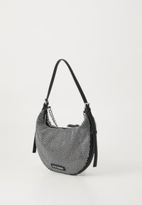 Sac à main noir en forme de croissant avec clous argentés, détail chaîne et bandoulière réglable, portant l'étiquette "Steve Madden."