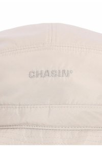 Jasnobeżowa czapka z przeszytymi szwami i haftowanym logo "CHASIN'". Gładki materiał z okrągłą koroną i płaskim daszkiem.