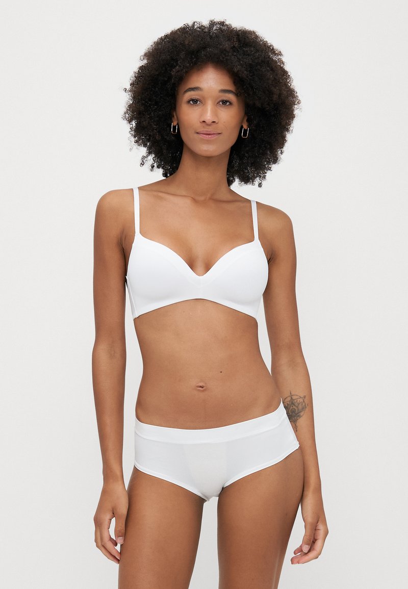 Biały biustonosz o gładkim, bezszwowym wzorze i regulowanymi ramiączkami, w zestawie z dopasowanymi białymi szortami o miękkiej talii.