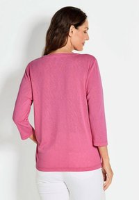 Rosa Langarm-T-Shirt aus weichem Stoff, mit lockerer Passform und Rundhalsauschnitt, mit umgeschlagenen Ärmeln und glatter Textur.