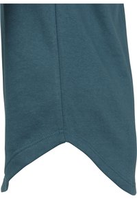 Maglietta di cotone color verde petrolio con orlo arrotondato, maniche corte e cuciture visibili. Tessuto morbido e design casual.